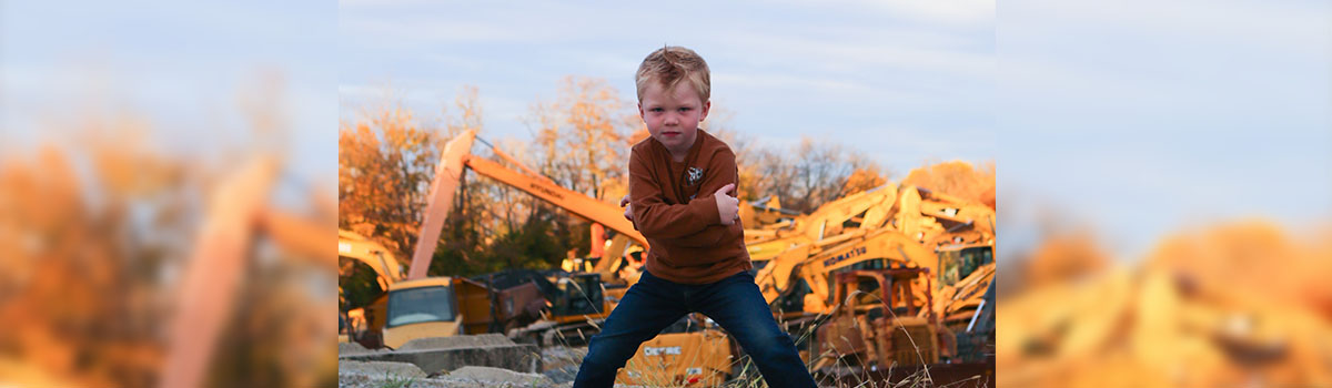 jake posing arms crossed with background of tractor inventory